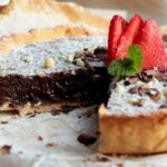 nutella tart topped with strawberries, confectioner's sugar and chopped almonds