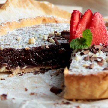 nutella tart topped with strawberries, confectioner's sugar and chopped almonds