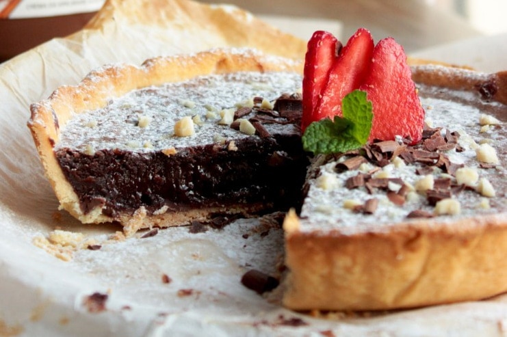 nutella tart topped with strawberries, confectioner's sugar and chopped almonds