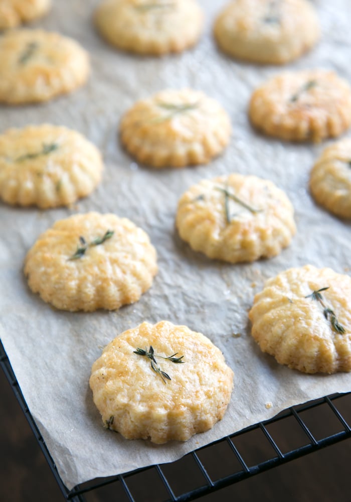 freshly baked cheese cookies on parchment paper over a cooling rack.