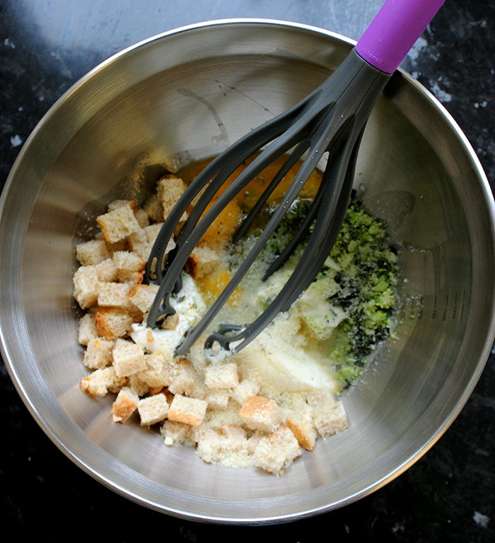 bowl with eggs, broccoli, bread cubes, cheese.