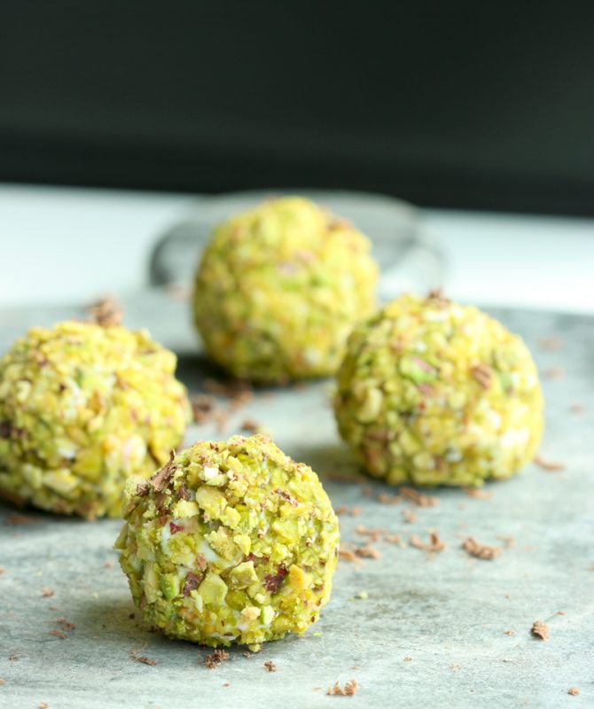 cannoli truffles with a pistachio crust served on a board.