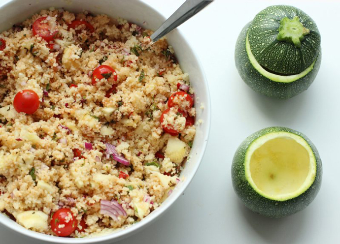 couscous salad in a bowl and round zucchini ready to be stuffed next to the bowl.