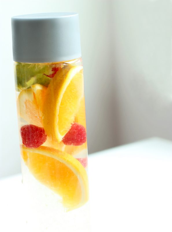 orange and raspberry fruit water in a glass bottle