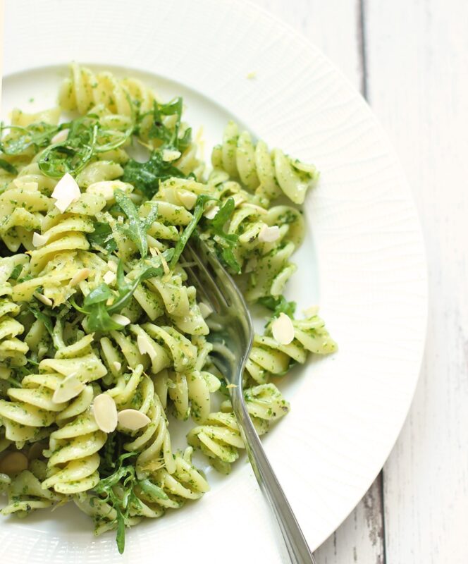 pasta with rocket pesto topped with almond flakes and served in a white dish