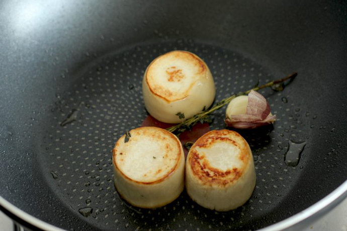 vegan scallops sauteed in a pan with thyme sprig and garlic.