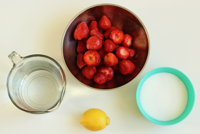 jar with water, bowl with strawberries, turquoise cup with sugar and 1 lemon