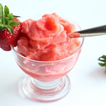 Strawberry Sicilian granita in a glass topped with a fresh strawberry and spoon