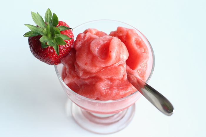 Strawberry Sicilian granita in a glass topped with a fresh strawberry and spoon