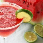 Watermelon margarita served in amartini glass and decorated with a lime slice.