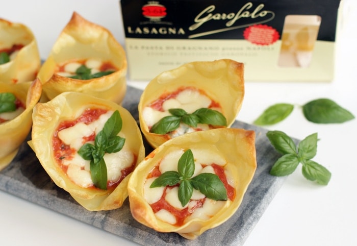 italian lasagna cups on a grey board next to basil leaves, garofalo lasagna pack in the background