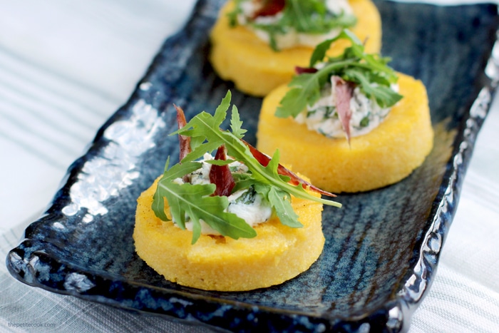 polenta crostini topped with jamon, ricotta and rocket leaves