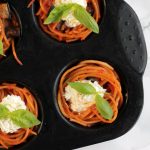 spaghetti cupcakes topped with ricotta and basil in a muffin tin