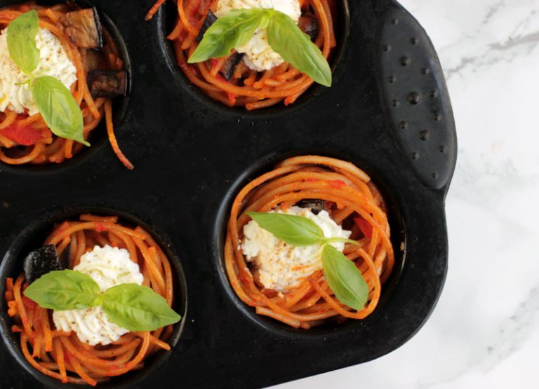 spaghetti cupcakes topped with ricotta and basil in a muffin tin