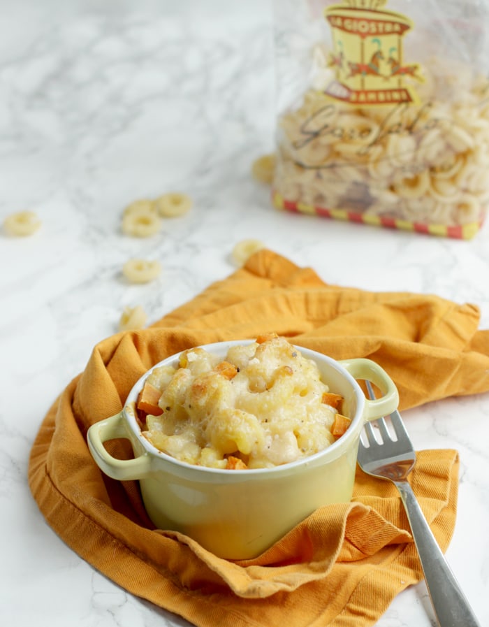 pumpkin mac and cheese in a small pot, pack of pasta in the background