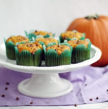 dairy-free pumpkin muffins on a cake stand next to a pumpkin