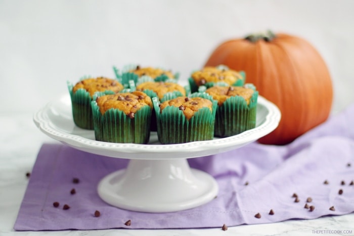 dairy-free pumpkin muffins on a cake stand next to a pumpkin