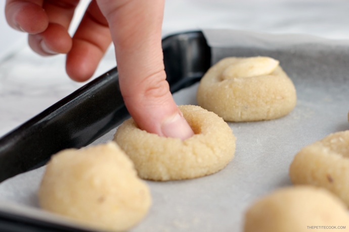 recipe step 4: thumb pressing down the center of the cookie ball to flatten it up slightly.