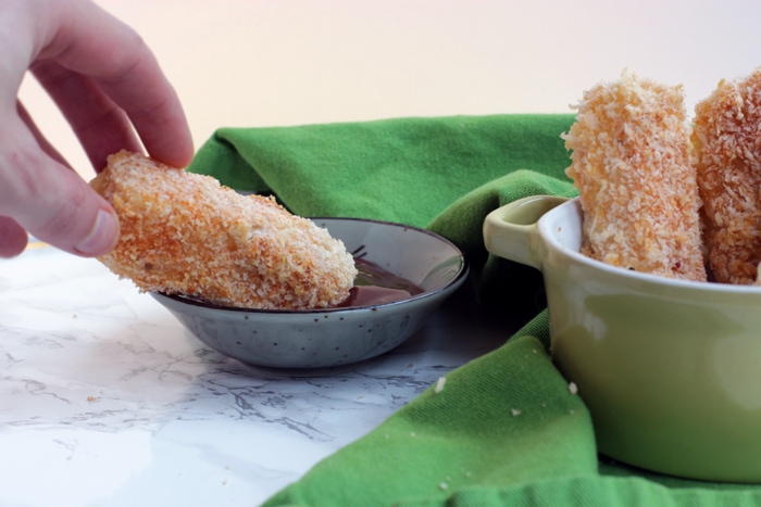 hand dipping a baked mozzarella stick