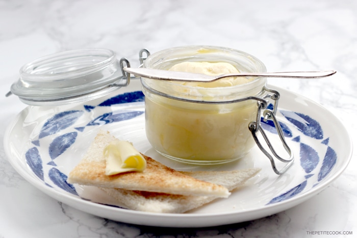 homemade butter in a jar with a knife over it, bread toasted with butter on top on a plate