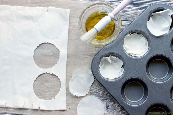 recipe step 1: phyllo pastry cut into rounds and arranged on a mini muffin tin, brusher and olive oil next to the tin.