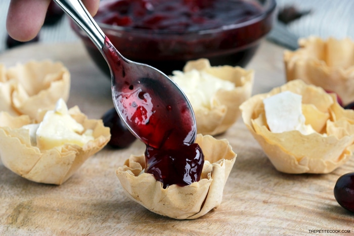 recipe step 3: phyllo cups with brie cheese topped with a spoonfool of cranberry sauce