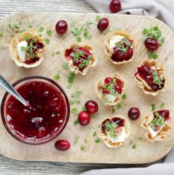 brie and cranberry cups on a wood board, served with homemade cranberry sauce.