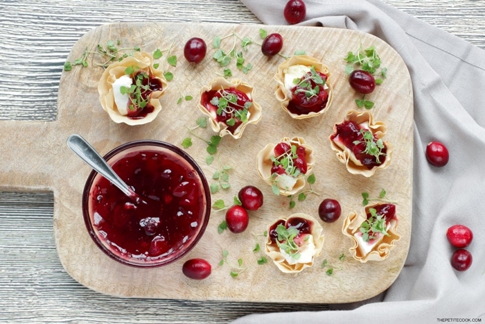 brie and cranberry cups on a wood board, served with homemade cranberry sauce.