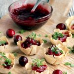 brie and cranberry cups on a wood board served with homemade cranberry sauce