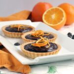 This delicious Mini Jaffa Tarts give a new twist to a classic British treat. The indulgent chocolate and orange combo makes a great dinner party dessert. Recipe from www.thepetitecook.com