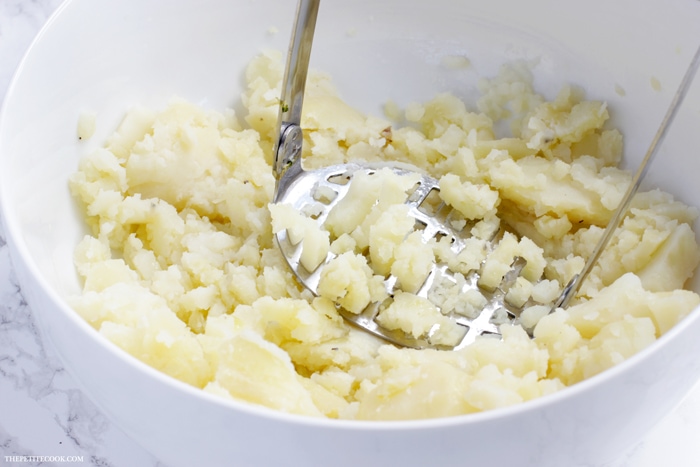 recipe step 1: mashed potatoes and a potato masher in a large white bowl