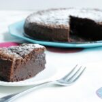 2-ingredient nutella cake slice in the focus with fork next to it, cake in the background on a turquoise plate.
