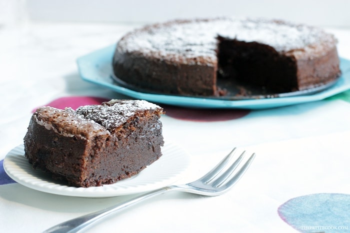 2-ingredient nutella cake slice in the focus with fork next to it, cake in the background on a turquoise plate.