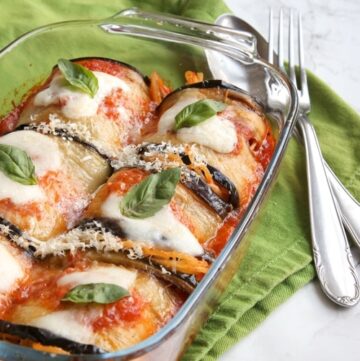 Eggplant spaghetti sandwiches in baking dish next to green napkin and spoon and fork on top