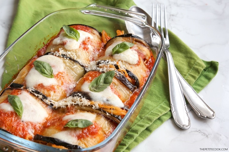 Eggplant spaghetti sandwiches in baking dish next to green napkin and spoon and fork on top