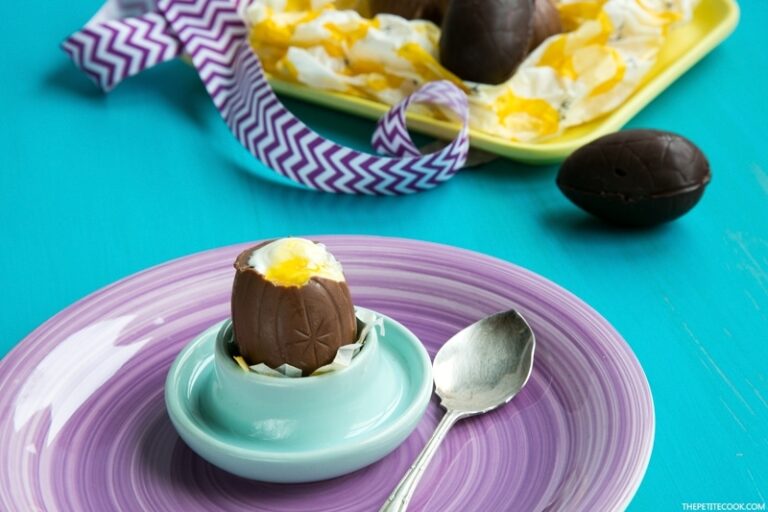 Cheesecake Chocolate Eggs on egg holder over a purple plate next to a spoon, more cheesecake eggs in the background