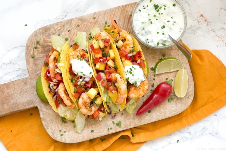 Give a vibrant refreshing twist on a Mexican favorite and try these Spicy Shrimp Tacos with Mango Salsa - The perfect Summer bite to share with friends! Recipe from www.thepetitecook.com