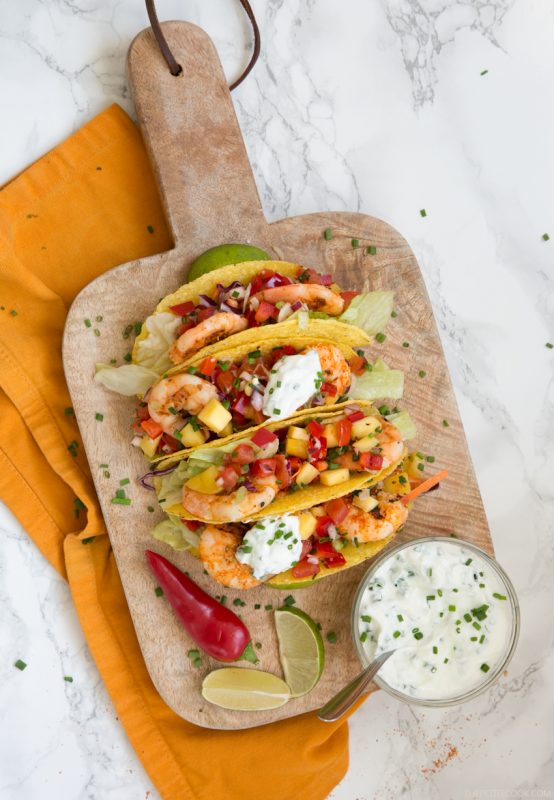 Give a vibrant refreshing twist on a Mexican favorite and try these Spicy Shrimp Tacos with Mango Salsa - The perfect Summer bite to share with friends! Recipe from www.thepetitecook.com