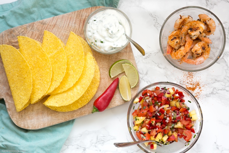 Give a vibrant refreshing twist on a Mexican favorite and try these Spicy Shrimp Tacos with Mango Salsa - The perfect Summer bite to share with friends! Recipe from www.thepetitecook.com