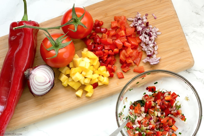 Give a vibrant refreshing twist on a Mexican favorite and try these Spicy Shrimp Tacos with Mango Salsa - The perfect Summer bite to share with friends! Recipe from www.thepetitecook.com