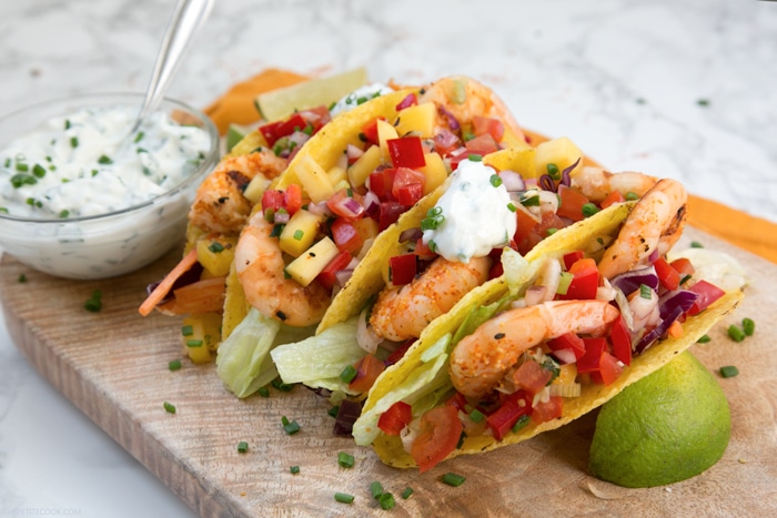 Give a vibrant refreshing twist on a Mexican favorite and try these Spicy Shrimp Tacos with Mango Salsa - The perfect Summer bite to share with friends! Recipe from www.thepetitecook.com