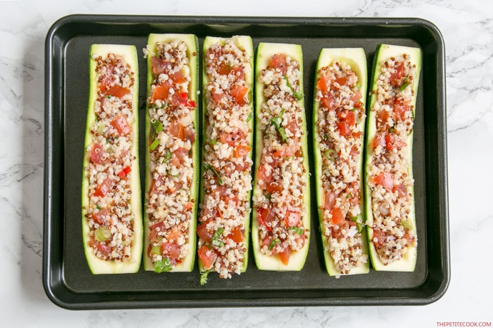 zucchini boats stuffed with quinoa and pico de gallo arranged on a baking tray