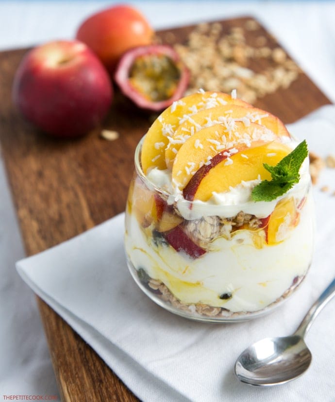 nectarine granola parfait in a glass topped with sliced nectarine, and a small mint sprig
