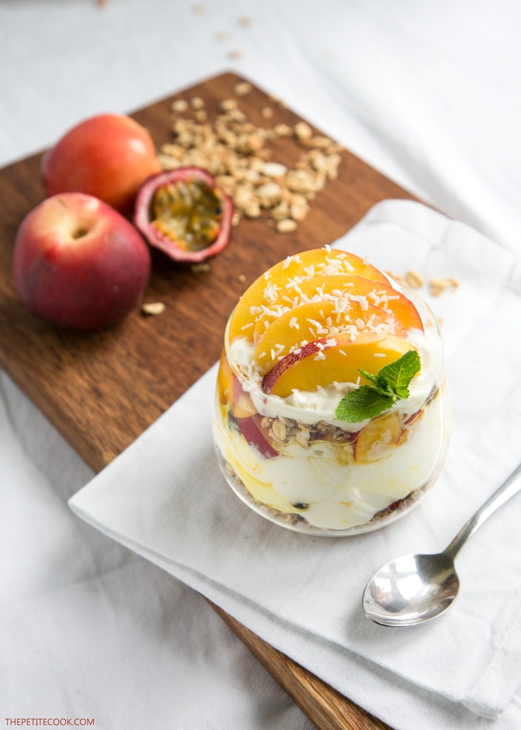 peach granola parfait in a glass topped with sliced nectarine, and a small mint sprig