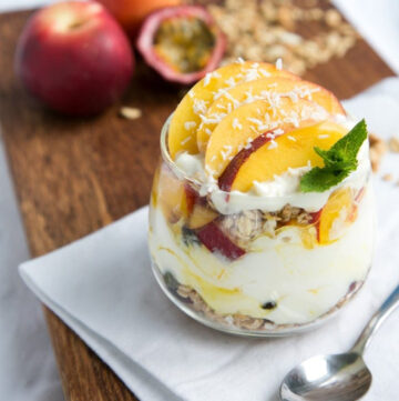 peach granola parfait in a glass topped with sliced nectarine, and a small mint sprig