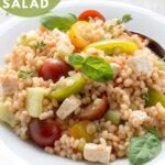 Greek pearl barley salad in a plate topped with basil leaves