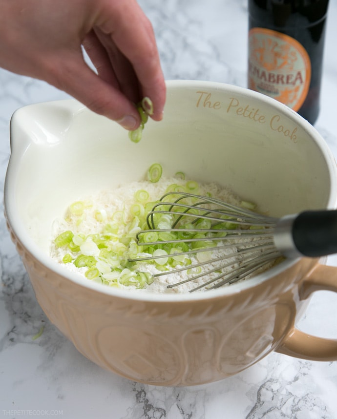 hand folding into a bowl spring onion, together with the dry mixture for the beer muffins