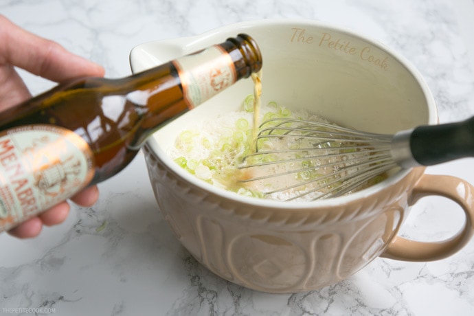 hand pouring the beer into the muffin mixture