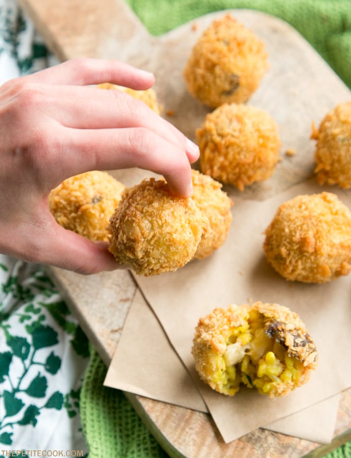 hand holding a mushroom arancini, more rice balls in the background