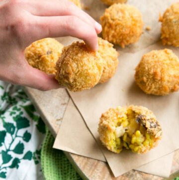 hand holding a mushroom arancini, more rice balls in the background